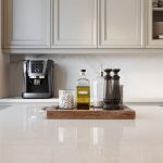A curated vignette of cooking essentials on a wooden tray, demonstrating strategic decluttering on a clean kitchen countertop.