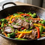 A vibrant, photorealistic close-up of a freshly prepared stir-fry dish. Tender, glistening slices of meat are mixed with bright, crisp red and yellow bell peppers, green broccoli florets, and thinly sliced carrots. A subtle, glossy sauce lightly coats the ingredients in a modern ceramic bowl, with soft, natural light emphasizing its fresh textures against a softly blurred background.