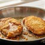 A close-up of two breaded meat cutlets frying in a hot skillet: one perfectly golden and crisp, the other with its breading peeling off messily, illustrating successful versus failed pan-frying.
