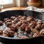 **Alt text:** Close-up of ground beef searing in a hot cast-iron skillet, showing deeply browned, caramelized meat crumbles sizzling in a thin layer of oil.