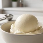 **Alt text:** A close-up photograph of a single, smooth scoop of vanilla bean ice cream slowly melting in a minimalist ceramic bowl, under soft, warm morning light.