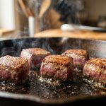 **Alt text:** Well-spaced cubes of beef searing in a hot cast-iron skillet, featuring a caramelized golden crust, sizzling oil, and gentle steam.