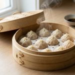**Alt text:** Fresh, pleated dumplings steaming inside a traditional woven bamboo steamer basket on a clean kitchen counter.